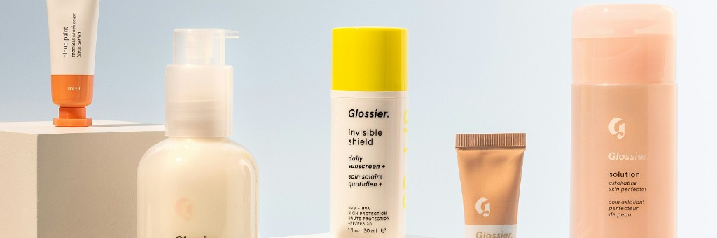 淡いブルーと白の背景に Glossier のスキンケア・メイク製品が並ぶバナー — Cloud Paint、日焼け止め、Solution など